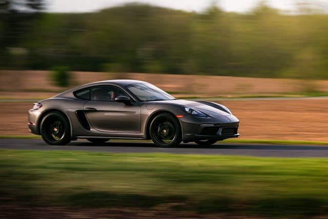 Gray sports car on a road with blurred greenery behind it